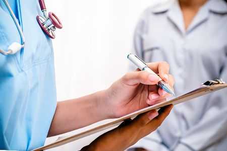 Врач пишет в медкарте пециентки